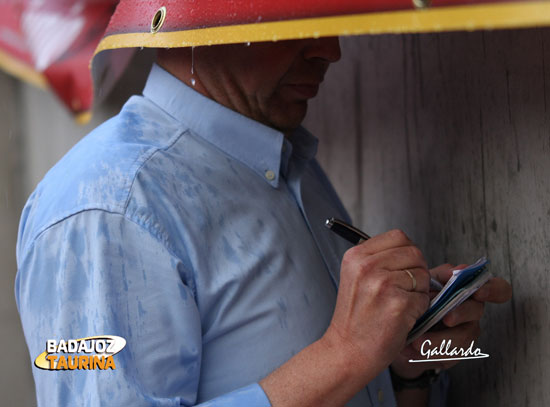 El ganadero tomando notas guarecido por una pancarta.